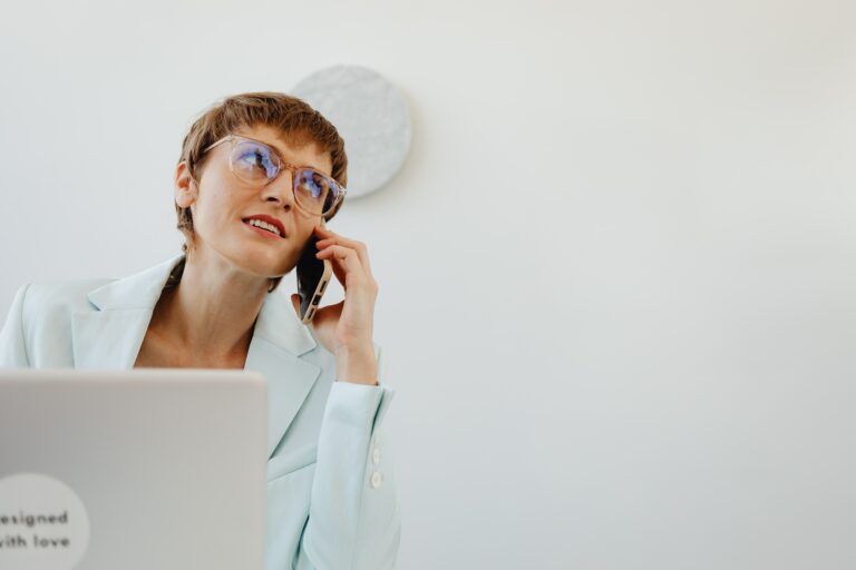 Mulher pratica multitasking, falando ao telefone enquanto trabalha num portátil.