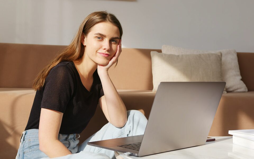 mulher jovem, que usa a inteligência emocional para ser mais disciplinada, está em frente a um laptop.