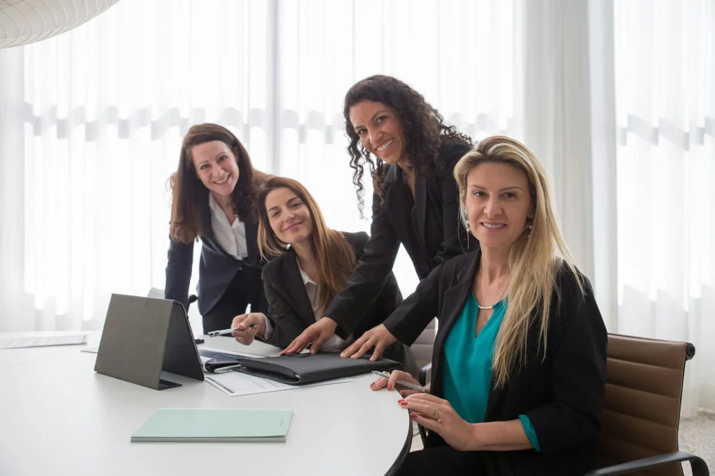 Equipa de mulheres num escritório, sorriem por terem um relacionamento forte e saudável que advém da importância do autoconhecimento.
