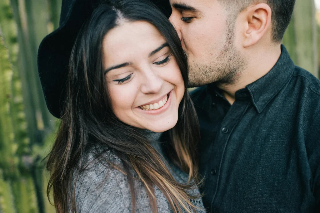 Homem beija mulher no cabelo enquanto ela sorri de olhos fechados por saber que o sucesso da sua relação teve como base a importância do autoconhecimento.